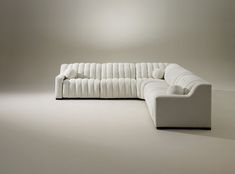 a white couch sitting on top of a floor next to a light brown wall in an empty room