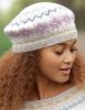 a woman with long hair wearing a white and purple knitted hat looking down at her cell phone