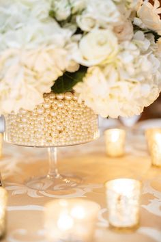 white flowers and candles are sitting on a table with an elegant centerpiece in the middle