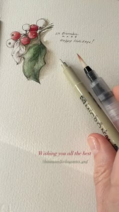 a person holding a pen and writing on a piece of paper with holly leaves drawn on it