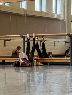 some people are laying on the floor with their feet in the air and reading books