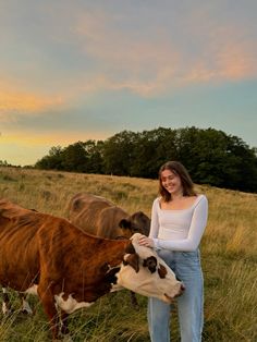 a woman standing next to two cows in a field