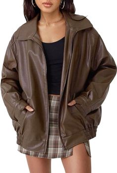 a woman wearing a brown leather jacket and plaid miniskirt with her hands on her hips