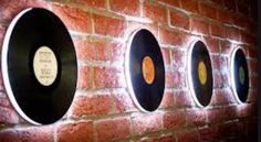 four vinyl records are mounted on a brick wall