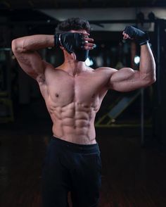 a shirtless man with boxing gloves on holding his hands up to his face and looking at the camera