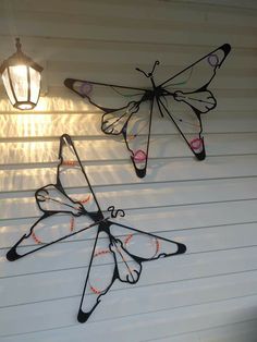 three metal butterflies hanging from the side of a building with a light on top of it