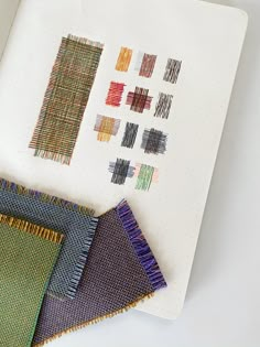 some fabric samples are laid out on top of a paper with colored pencils in them