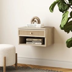 a white chair sitting next to a wooden table with books on it and a potted plant in the corner