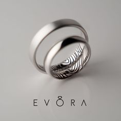 two wedding rings with feathers on them are shown in this image, and the word ev 8ra is written below it