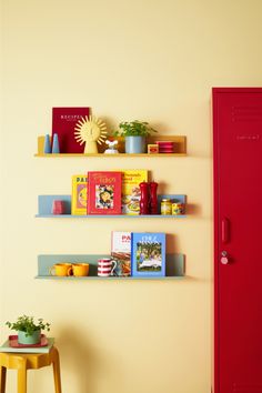 two shelves with books on them are next to a red locker and yellow table in the corner