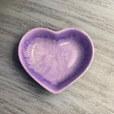 a purple heart shaped bowl sitting on top of a wooden table