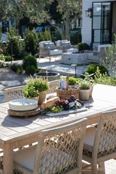 an outdoor dining table set up with plates and bowls of food on top of it