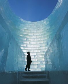 a person standing in an ice cave with stairs leading up to the top and bottom