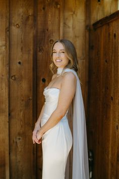 a woman in a white wedding dress and veil posing for a photo with her hands on her hips