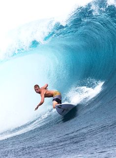 a man riding a wave on top of a surfboard in the ocean with blue water