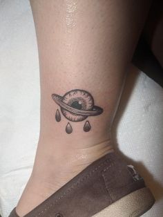 a small saturn tattoo on the ankle