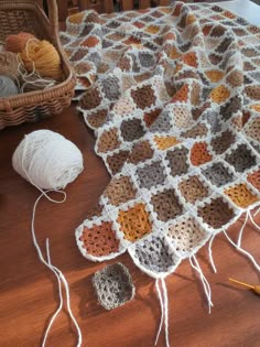 a crocheted afghan is sitting on the floor next to yarn