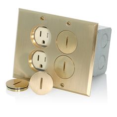 an electrical outlet with three outlets and two plates on the wall, one is gold