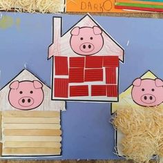 a paper cut out of two pigs in front of a house with hay on the ground