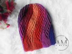 a multicolored knitted hat laying on top of a white furnishing