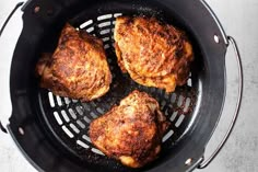 four pieces of chicken cooking in a frying pan