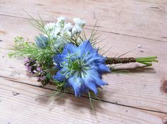 a bouquet of blue and white flowers sitting on top of a wooden table next to a piece of wood