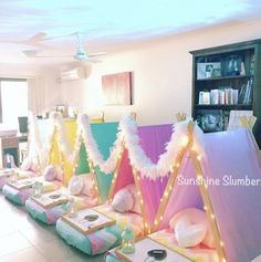 a room filled with lots of pillows and lights on top of each other in front of a bookshelf