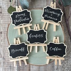 small chalkboard signs on wooden clothes pins with writing in black and white, sitting on a green plate