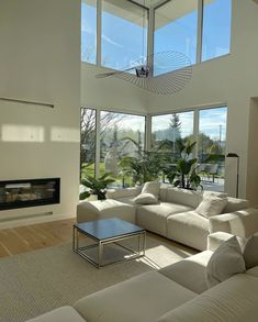 a living room with white furniture and large windows looking out onto the outdoors area,