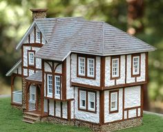 a model house sitting on top of a lush green field