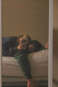 two people laying on a bed taking a selfie