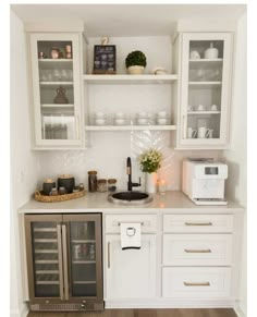 a kitchen with white cabinets and stainless steel appliance on the counter top, along with a wine cooler