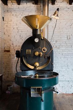 an old fashioned steam engine sitting on top of a wooden floor next to a brick wall