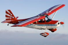 a small red and white plane flying in the sky