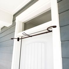 an open white door on the side of a gray and white house with blue siding