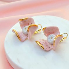 A luxurious model, these gilded earrings are perfect for a fresh look. They are made from pink porcelain with a delicate gold effect. Stainless steel findings. Each product is handmade which makes it unique. Size (approx): 3x3 cm (1.18x1.18 in). Weight / pair (approx): 15 g (0.52 oz). The product images are for illustrative purposes only and may differ slightly from the actual product. The size, weight and design of the product may vary slightly. Other ceramic jewelry, brooches and cat earrings Pink Enamel Flower-shaped Earrings, Pink Flower-shaped Enamel Earrings, Pink Flower Enamel Earrings, Pink Enamel Jewelry With Matching Earrings, Feminine Gold Plated Earrings For Gift, Elegant Pink Enamel Earrings, Feminine Yellow Gold Earrings For Gift, Feminine Yellow Gold Earrings Gift, Pink Enamel Earrings For Gift