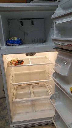 an open refrigerator with the door wide open and food on the shelf still in it