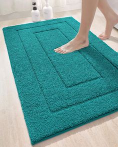 a person standing on top of a blue rug next to a bathtub and toilet