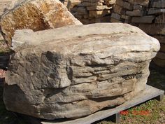 a large rock sitting on top of a wooden bench next to a pile of rocks