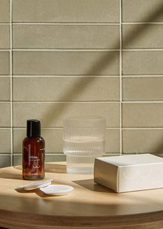 a table with a glass, bottle and soap dispenser sitting on it