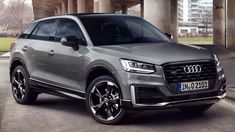 the new audi q3 suv is parked in front of an overpassed bridge