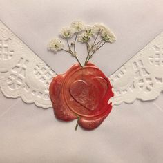 a wax seal with flowers in it on top of a white lace table cloth and doily