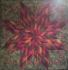 a quilted wall hanging with a large star on it's side and another design in the middle