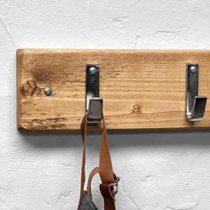 a wooden coat rack with two hooks and a bag hanging from it's side