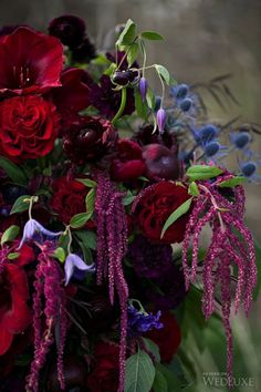 a bouquet of flowers with purple and red blooms in the center, surrounded by greenery