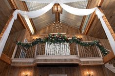 the inside of a building decorated with white drapes and greenery on the ceiling