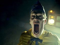 a creepy clown with his mouth open in the dark