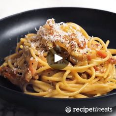 a black bowl filled with pasta and sauce