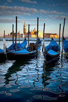 several gondolas are tied to poles in the water