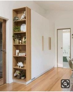 an open bookcase in the middle of a room with wooden floors and white walls